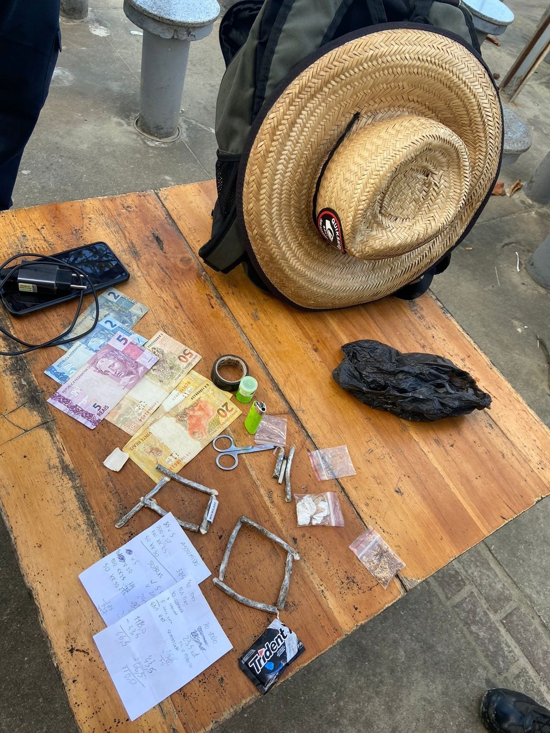 Em revista em sua mochila, encontraram 10 cigarros de maconha, R$ 99 reais, papéis de contabilidade do tráfico, além de um celular e outros objetos