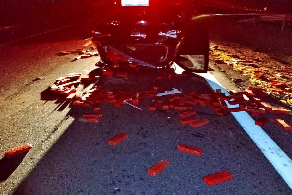 Um carro, que capotou em um acidente, foi abandonado com as rodas para cima, e 375 kg de maconha ficaram espalhados pela pista