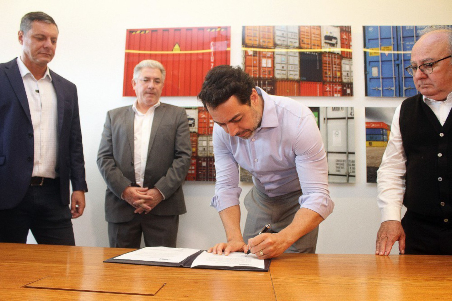 Anderson Pomini assina termo ao lado do prefeito de Santos, Rogério Santos, e dirigente da FIPS