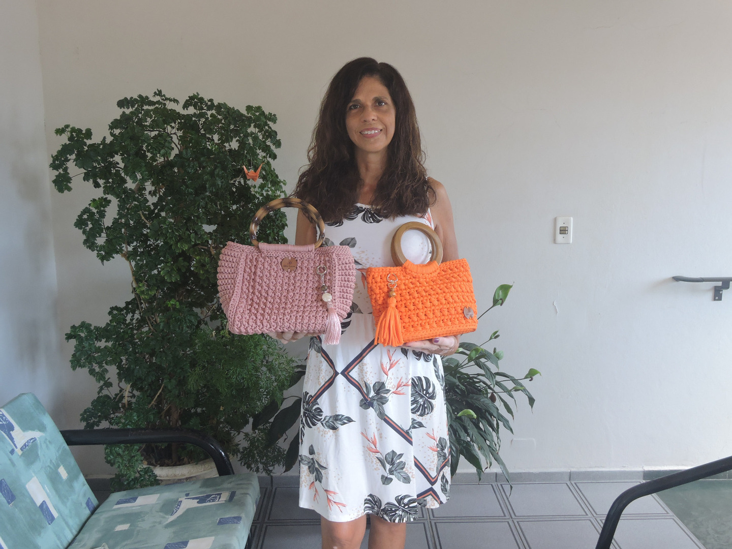 A artesã Célia Regina mostra as bolsas feitas em crochê de vários modelos e cores, em Itanhaém