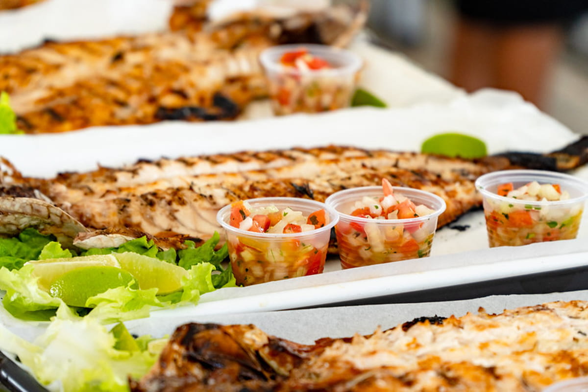 O prato vem com uma tainha espalmada na brasa, junto de arroz, farofa, vinagrete e pão, o que alimenta bem três pessoas