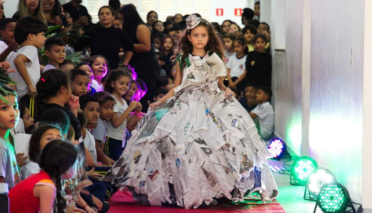 Guiadas pela criatividade, as crianças transformaram materiais como jornal, papel, revistas, CDs, garrafas plásticas e sacos de lixo em figurinos surpreendentes