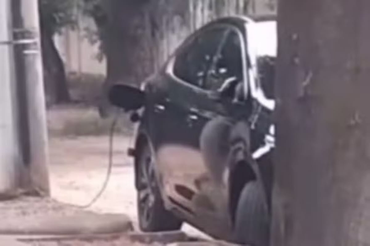 Nas imagens, o veículo aparece estacionado na rua com um cabo de energia estendido até a base do poste, configurando o popular e ilegal "gato"