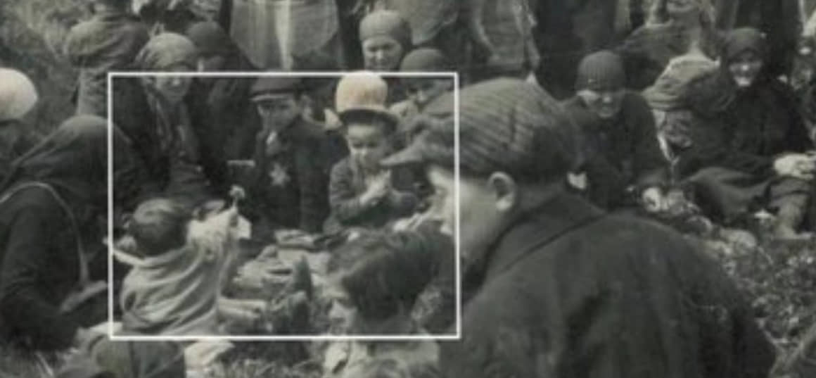 Menino oferece flor a outra criança durante o holocausto