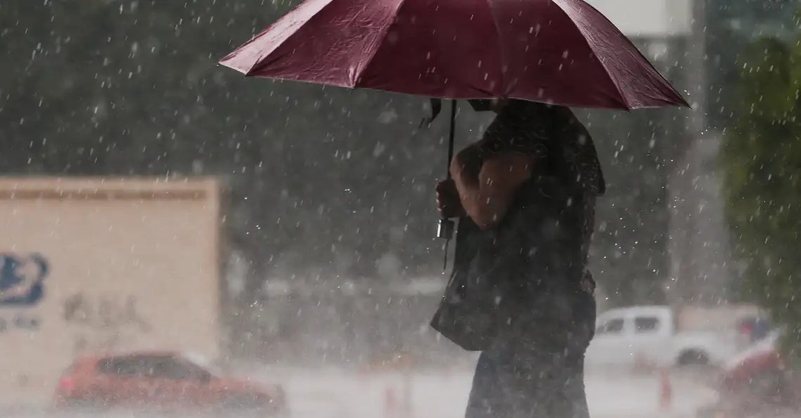 Mulher tenta de proteger da chuva durante ciclone em SP