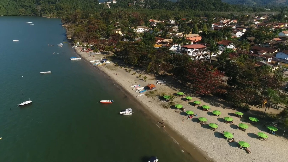 A água tranquila e as marolas discretas revelam áreas onde a lama escura aflora com facilidade
