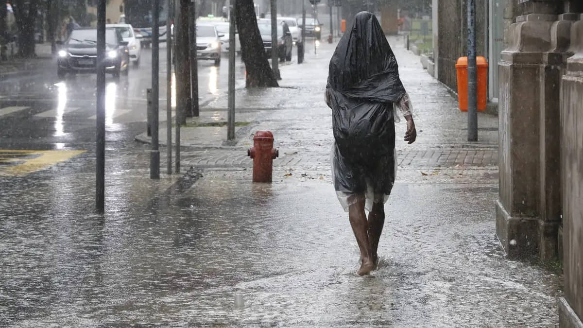 Morador em situação de rua tenta se proteger de chuva forte