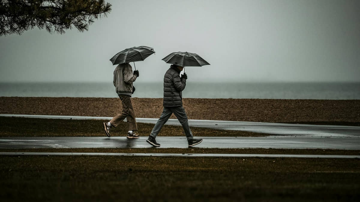 Casal faz caminhada à beira-mar durante chuva