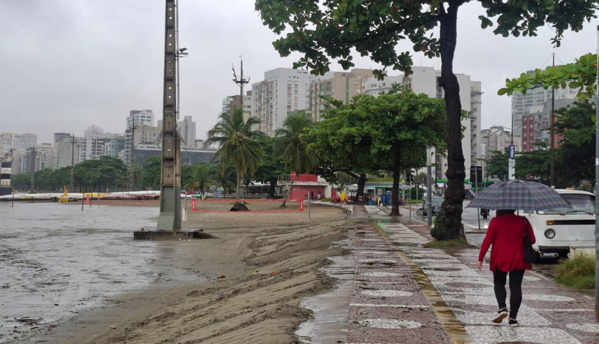 Mulher caminha com guarda-chuva em manhã chuvosa em Santos