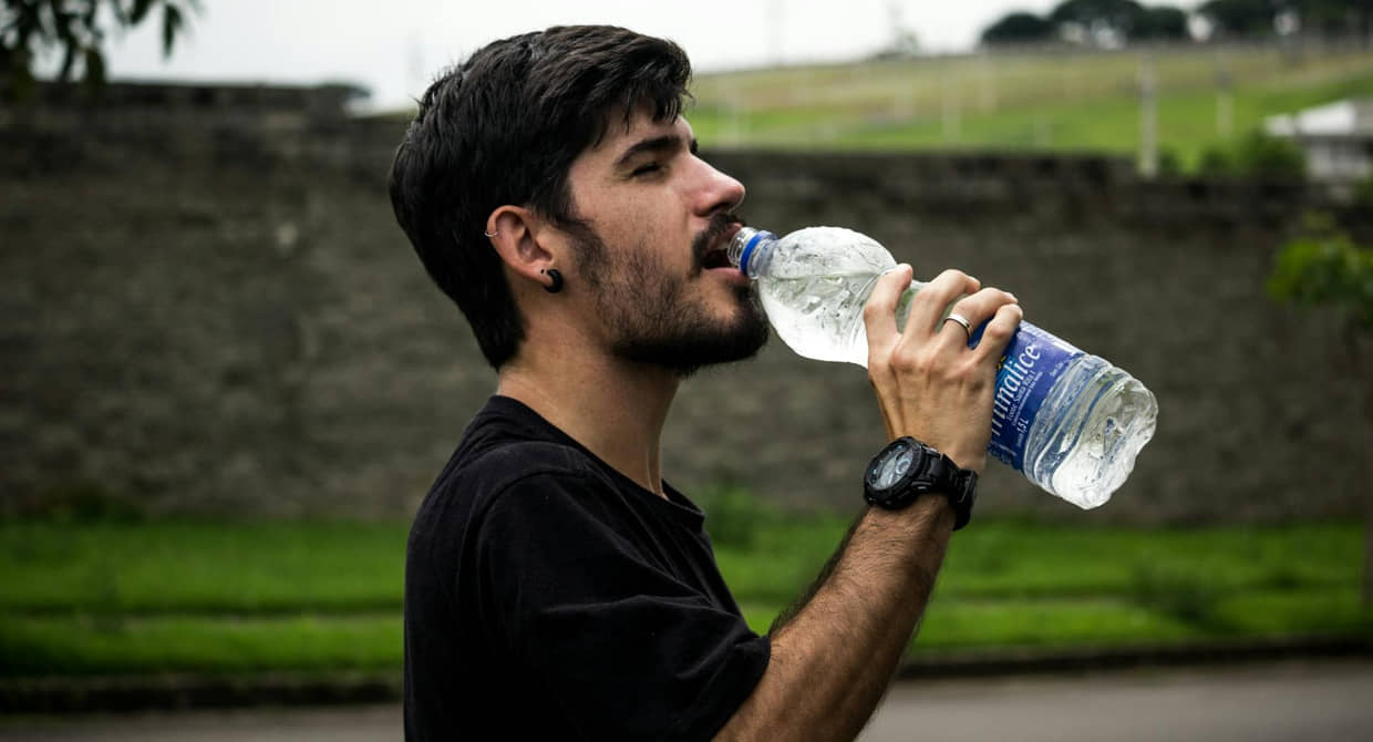 Homem bebe água gelada em dia de calor forte no Brasil