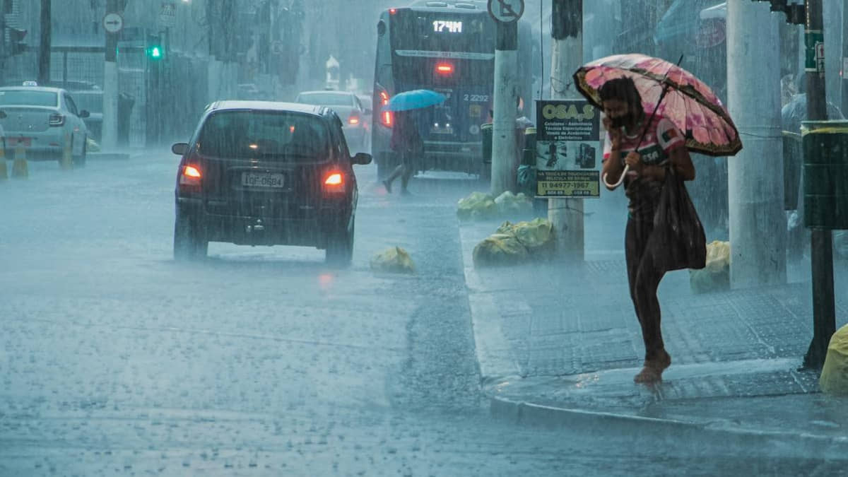 Mulher tenta atravessar a rua em tarde de forte temporal